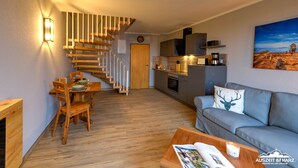 Una sala de estar moderna con una escalera, un comedor y una cocina.