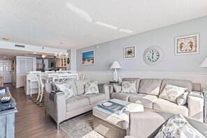 A modern living room with a sofa set, a coffee table, and a dining area with a white table and chairs. - 3 Bdrm Oceanfront Condo- 4 Bds- Pool- Near Main St (North Myrtle Beach)