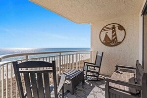 A balcony with a view of the ocean, featuring a circular wall decoration, a small table, and two chairs. - 3 Bdrm Oceanfront Condo- 4 Bds- Pool- Near Main St (North Myrtle Beach)
