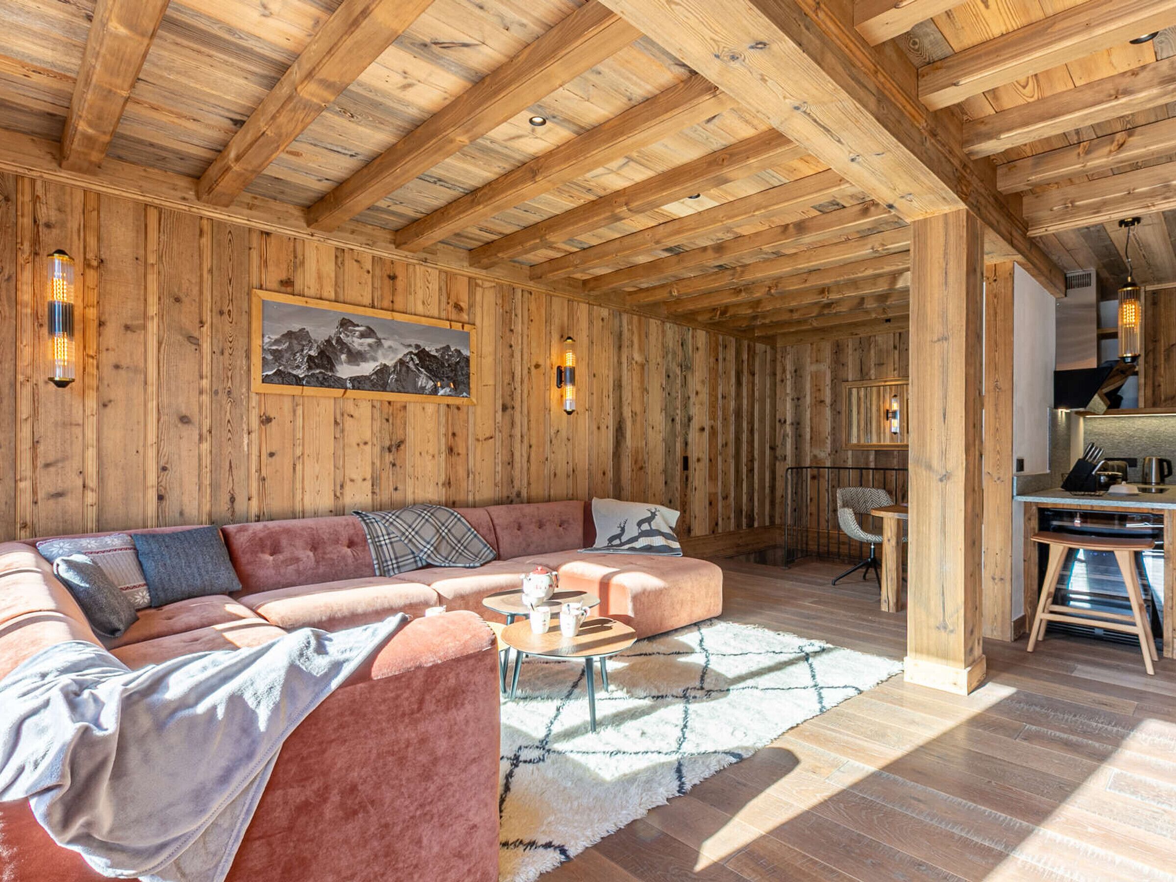 A cozy wooden interior with a sectional sofa, a dining area, and a kitchen.