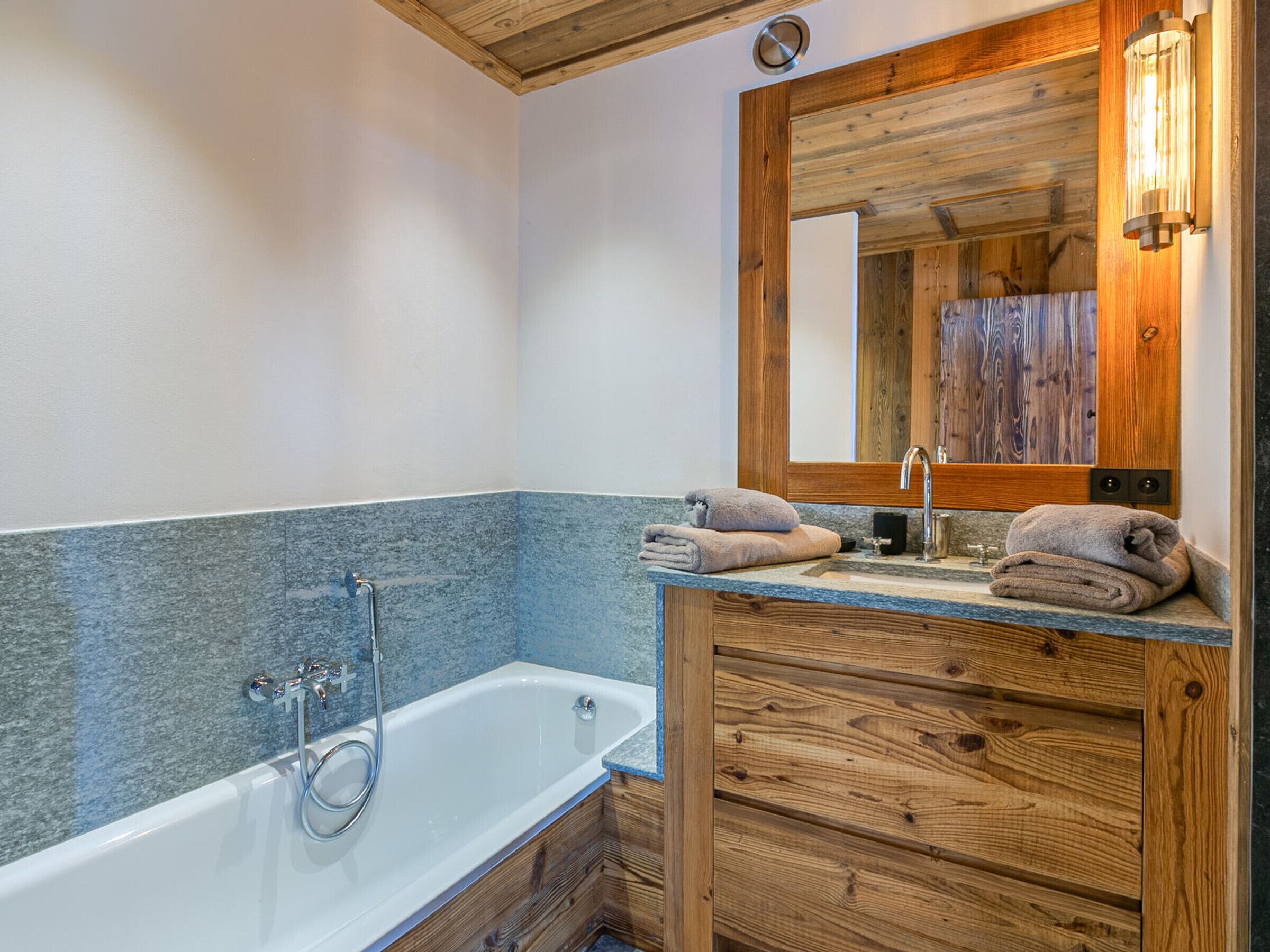 Een moderne badkamer met een vrijstaand bad, houten wastafelmeubel en een grote spiegel.