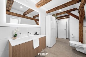 Une salle de bain moderne avec des poutres en bois, un lavabo blanc et des toilettes.