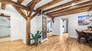 Una habitación amplia con vigas de madera, un comedor con mesa y sillas, y un ventanal con vistas.