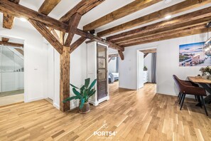 Una habitación amplia con vigas de madera, un comedor con mesa y sillas, y un ventanal con vistas.