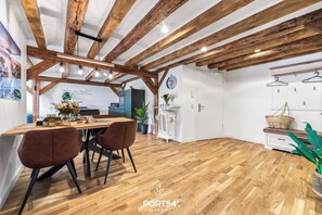 Eine moderne Küche mit Holzbalken, einem Essbereich mit braunen Stühlen und einem weißen Kühlschrank.