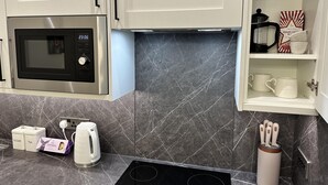 A modern kitchen with a built-in microwave, a coffee maker, and a kettle on the counter. - Captivating 2-bed Apartment in Brighton (Brighton)