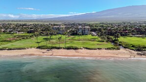 A coastal resort with a beachfront, a golf course, and a mountain backdrop.