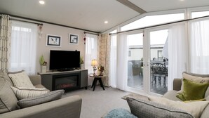 A living room with a flat-screen TV, a fireplace, and a balcony with a table and chairs.