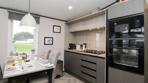 A modern kitchen with a dining area, equipped with a gas stove, oven, and coffee maker.