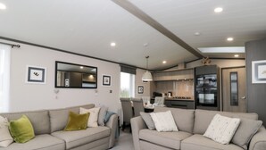 A modern living room with two sofas, a dining area, and a kitchen.