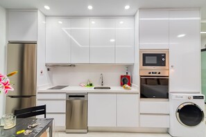 Une cuisine moderne équipée d’appareils électroménagers en acier inoxydable, d’un four à micro-ondes encastré et d’un lave-linge.