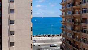 Un edificio alto con varios balcones que dan a una carretera costera y al mar.