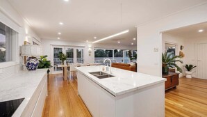 Een moderne keuken met een centraal eiland, houten vloer en uitzicht op de omgeving.
