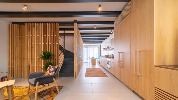 Une cuisine moderne avec des meubles en bois, une cuisinière encastrée et un escalier menant à un autre niveau.