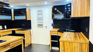 Una cocina moderna con armarios de madera, encimeras negras y una puerta blanca con un cartel de normas de la cocina.