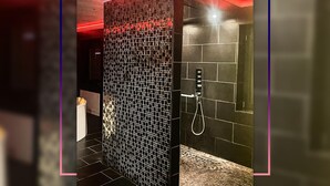 Un baño moderno con pared de azulejos negros y zona de ducha.