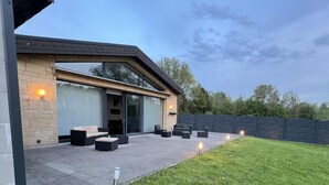 Una casa moderna con un patio amoblado, mobiliario exterior y una pared de piedra.