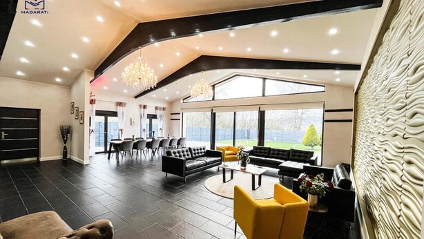 Un espacio habitable amplio con techo alto, muebles modernos y ventanas grandes que ofrecen vistas al exterior.