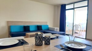 Un coin repas avec une table dressée pour deux personnes, deux chandeliers décorés et une vue sur un balcon aménagé avec du mobilier d’extérieur.