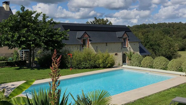 Una casa circondata dal verde con una piscina e un cielo sereno.