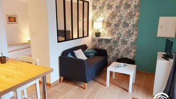 A modern living room with a sofa, a small table, a TV, and a patterned wallpaper.
