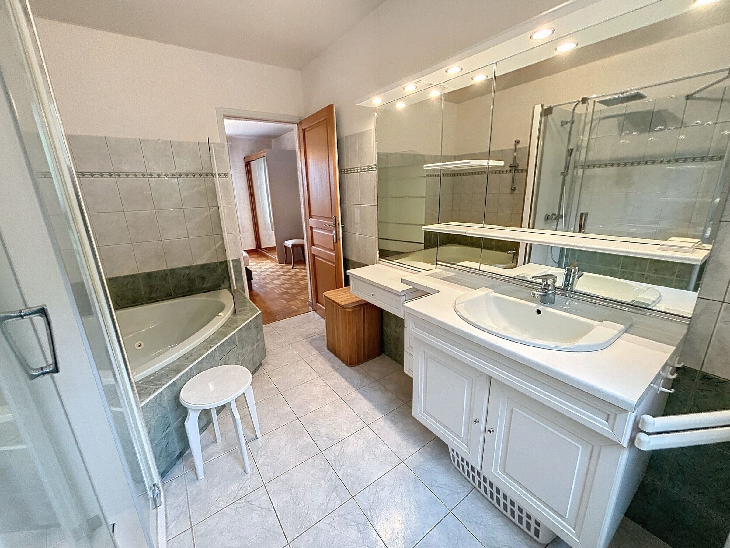 A modern bathroom with a bathtub, a sink, and a large mirror.