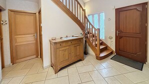A staircase with wooden railings, a wooden door, and a cabinet with a bowl on top.