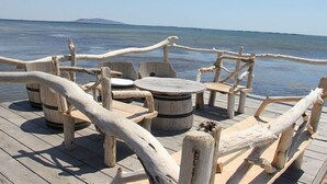 A wooden deck with rustic furniture and a rope barrier overlooking a body of water. - Beachside 2-BR Apartment for 5 with Private Parking & Terrace in Marseillan (Marseillan-Plage)