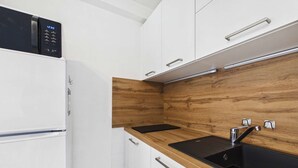 Eine moderne Küche mit weißen Schränken, einer Holz-Spritzschutzwand, einer schwarzen Arbeitsplatte und einem Edelstahl-Spülbecken.