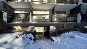 A multi-story building with balconies, a snow-covered ground, and a bench in the entrance area. - Cozy Studio with Balcony, Sleeps 3, Near Slopes and Amenities (La Salle-les-Alpes)