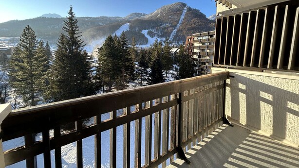 A balcony with a view of snow-covered mountains and pine trees. - Cozy Studio with Balcony, Sleeps 3, Near Slopes and Amenities (La Salle-les-Alpes)
