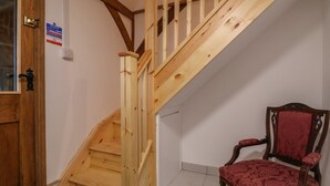 A wooden staircase with a red upholstered chair in a room with white walls. - The Chicken Coop (Shrewsbury)