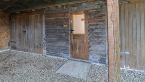 A rustic barn-style building with a wooden door and two large wooden doors. - The Chicken Coop (Shrewsbury)