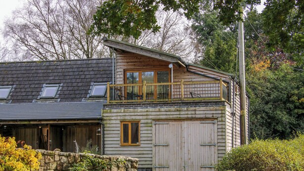 A two-story wooden house with a balcony, a stone wall, and a wooden gate. - The Chicken Coop (Shrewsbury)