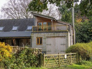 A two-story wooden house with a balcony, a stone wall, and a wooden gate. - The Chicken Coop (Shrewsbury)
