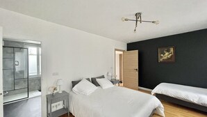 A bedroom with a bed, bedside tables, a nightstand, a mirror, a door, and a painting on the wall. - Chambre Quadruple Avec Salle de Bains Privative à 10 Minutes de Disneyland Paris (Couilly-Pont-aux-Dames)
