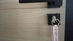 A wooden door with a black handle and a keychain with a pink tag. - Chambre Quadruple Avec Salle de Bains Privative à 10 Minutes de Disneyland Paris (Couilly-Pont-aux-Dames)