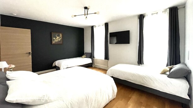 A modern hotel room with two single beds, a large window with curtains, a flat-screen TV, and a radiator. - Chambre Quadruple Avec Salle de Bains Privative à 10 Minutes de Disneyland Paris (Couilly-Pont-aux-Dames)