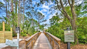 A wooden boardwalk leading through a forested area with a sign indicating new parking rates. - Coastal Charm in the Heart of Hilton Head Island (Hilton Head Island)