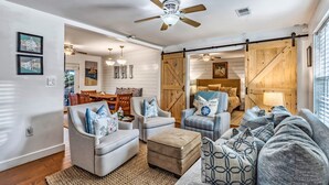 A spacious living room with a large sofa, two armchairs, a coffee table, and a ceiling fan. There is a dining area with a table and chairs visible in the background. - Coastal Charm in the Heart of Hilton Head Island (Hilton Head Island)