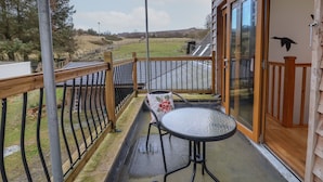 A balcony with a glass door, a table, and a chair. - The Duckhouse (Shrewsbury)
