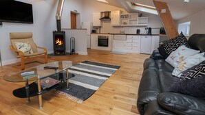 A modern living room with a glass coffee table, a leather sofa, a fireplace, and a kitchen in the background. - The Duckhouse (Shrewsbury)