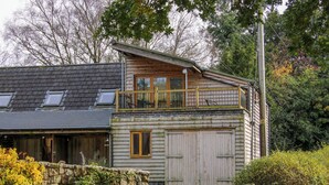 A two-story wooden house with a balcony, a stone wall, and a wooden gate. - The Duckhouse (Shrewsbury)