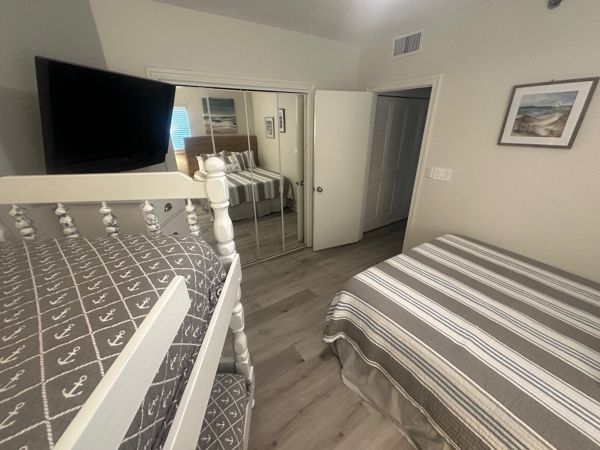 A bedroom with a bed, a TV, a wardrobe, and a door leading to another room.