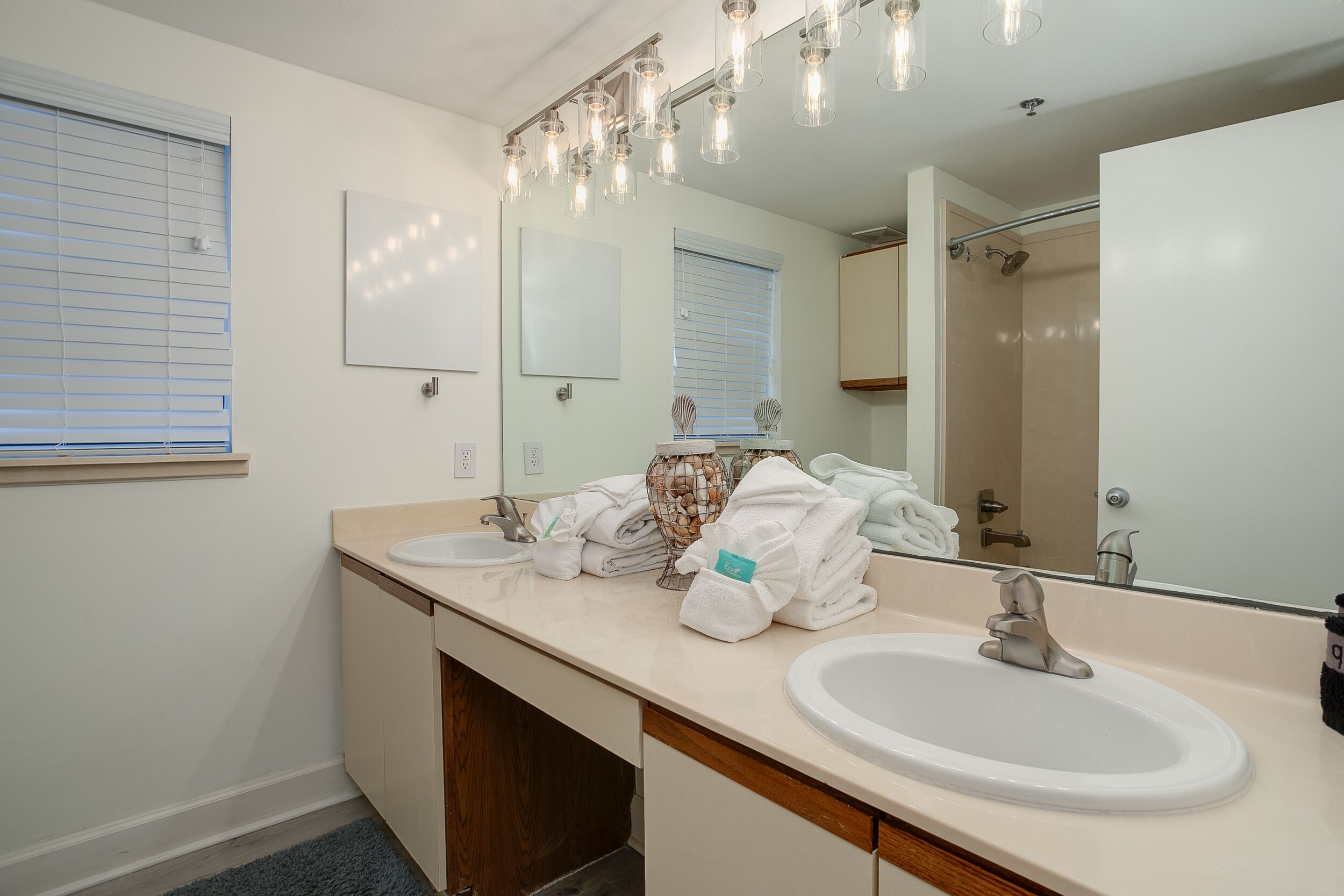 A modern bathroom with two sinks, a large mirror, and a shower.