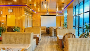 Een gezellig restaurantinterieur met houten wanden en plafond, rieten meubels en grote ramen met uitzicht.