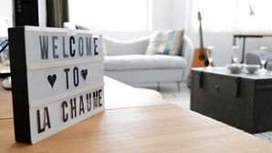 A lightbox with "WELCOME TO LA CHAU" on a wooden table in a living room.