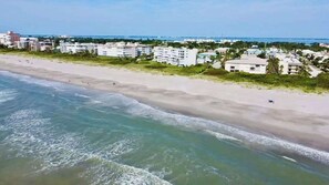 A coastal hotel with a beachfront view, multiple buildings, and a sandy beach.