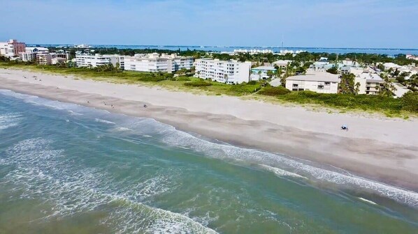 An aerial view of a beach with buildings in the background. - Fillmore Unit 10 (Cape Canaveral)