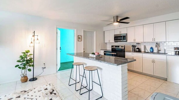 A modern kitchen with white cabinets, a granite countertop, and a built-in oven. - Fillmore Unit 10 | 2BR/1BA (Cape Canaveral)